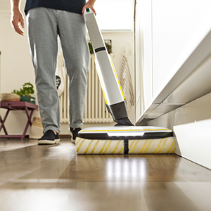 A person cleaning the edge of a skirting board